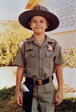 Christopher, age 7, smiling in his official police uniform.