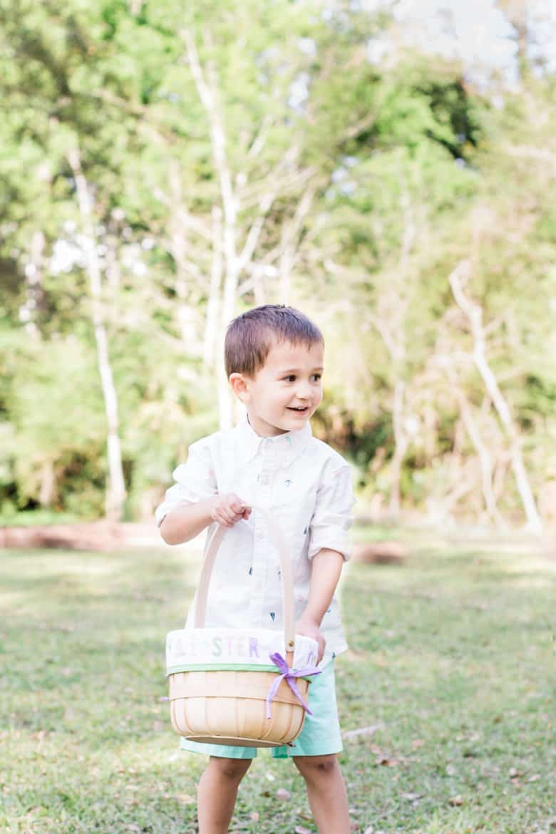Toddler boy walks on the lawn carrying an easter basket wearing kids easter outfit
