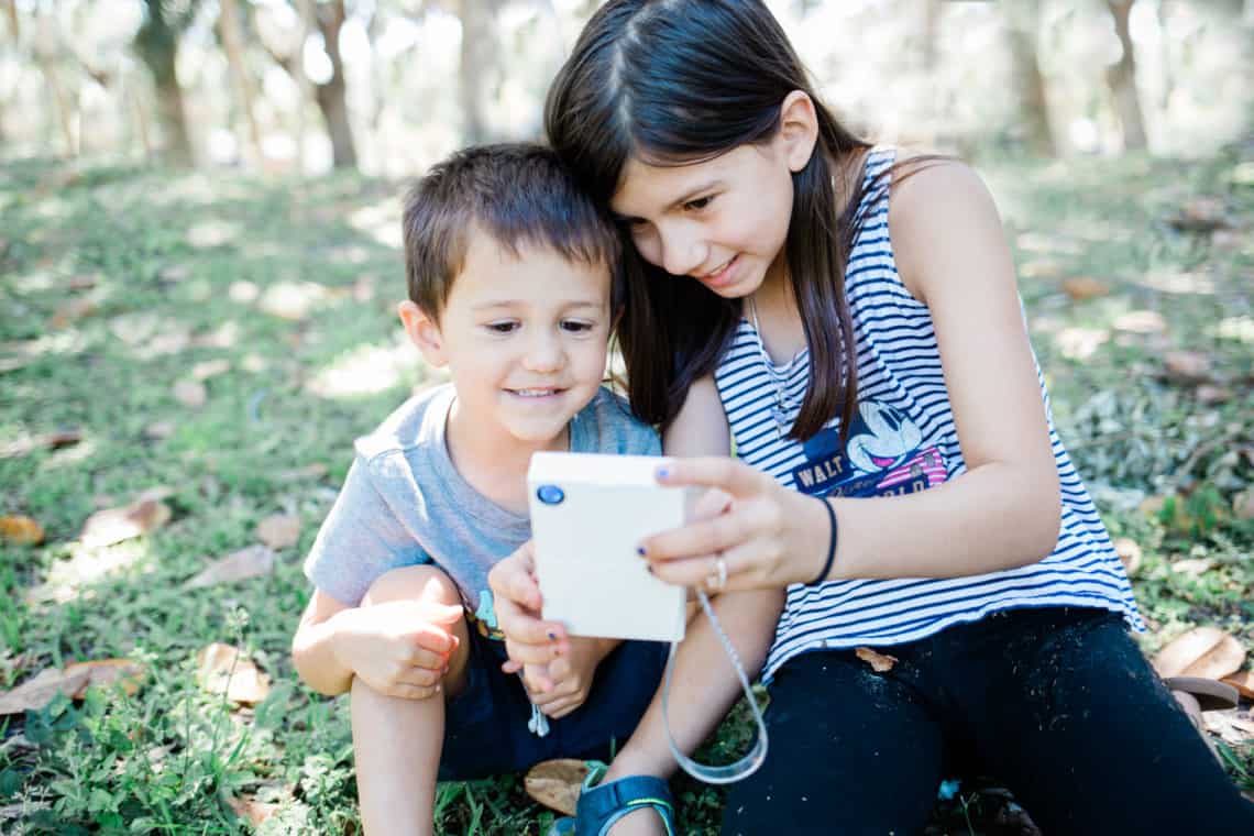 two young kids taking a selfie with the Polaroid Mint Camera in an article featuring for the creative way my kid is surviving deployment 