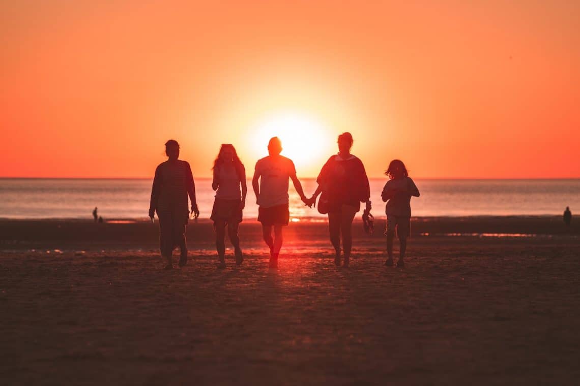 silhouette photo of five person walking on seashore during