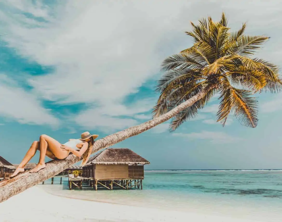 woman lying on coconut tree trunk at beach tropical vacation