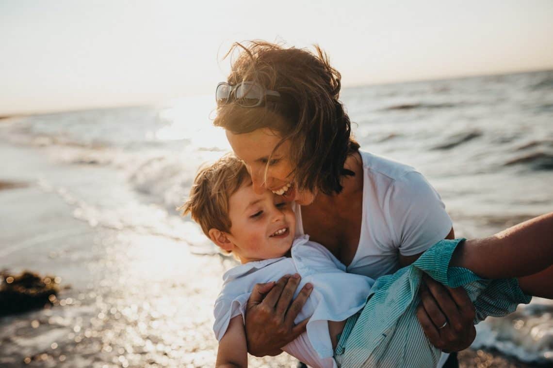 mother holding boy at beach