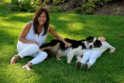 woman sitting on grass petting a dog relaxing with son